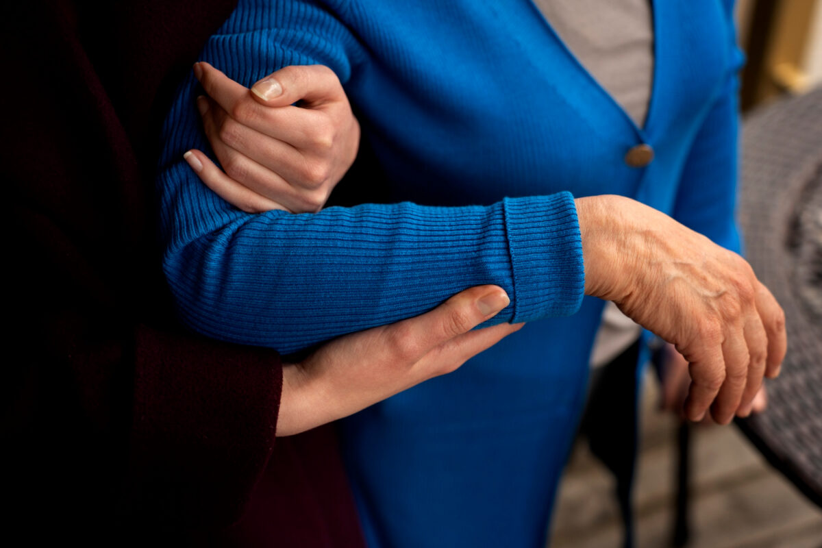 Un aidant aide une dame agée à se tenir debout